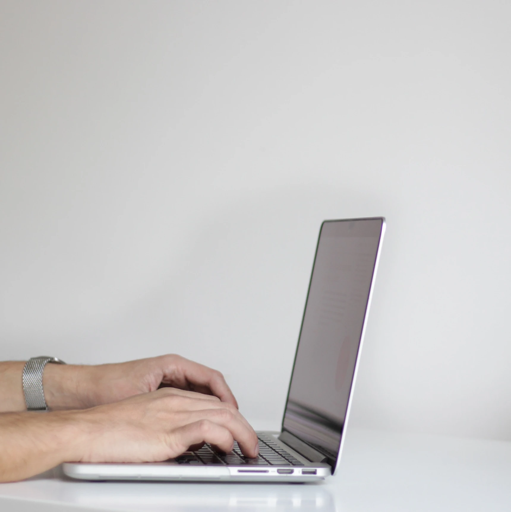 Image of hands typing over a laptop keyboard